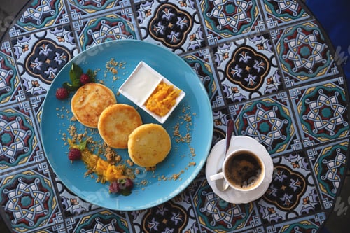Preview: Beautiful ruddy three cheese pancakes on a blue plate on a bright restaurant table with orange peel
