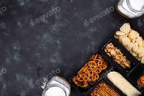 Preview: a variety of snacks on the box for beer on a concrete black table