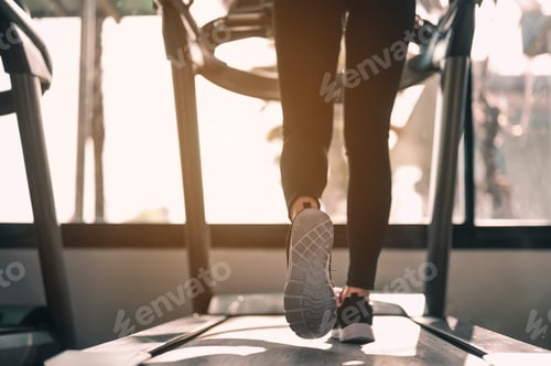Preview: Legs and feet of women walking on the treadmill in the gym for good health and strength at sunset.