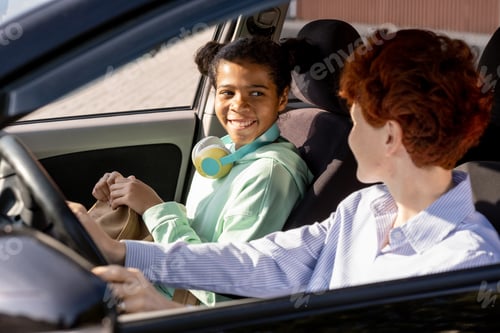 Preview: Happy mixed-race girl looking at young woman in car