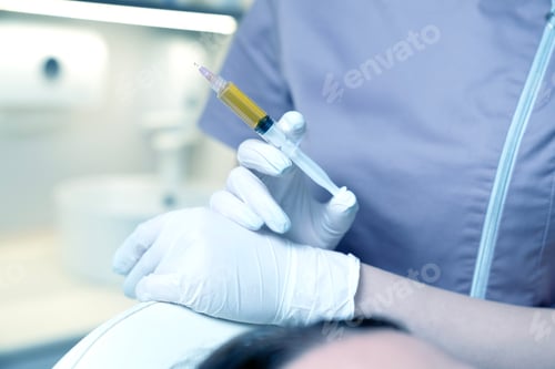 Preview: Plasma lifting - close-up of a doctor's hand in blue rubber gloves with a syringe