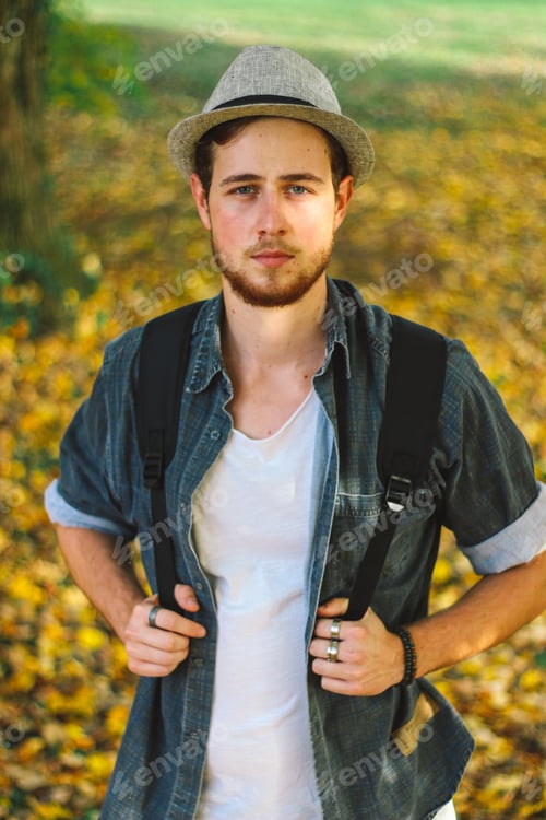 Preview: Vertical selective focus shot of an attractive guy in an autumn park
