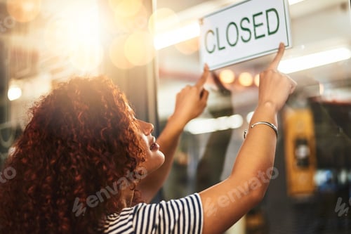 Preview: Its the end of another successful day. Shot of a young woman hanging up a closed sign in her store.