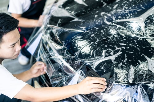 Preview: Asian car film protection male worker installing film to black color car in garage