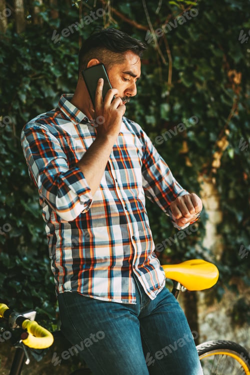 Man on Phone Leaning on Bike Outdoors
