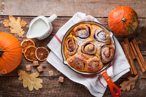 Preview: Cinnabon cinnamon rolls buns with pumpkin, nut, caramel and sugar cream iced on rustic wooden backgr
