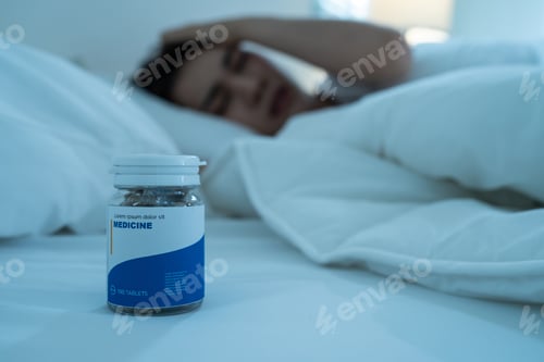 Preview: Asian beautiful sick girl in pajamas take medicine before sleep on bed. Health-medical concept.