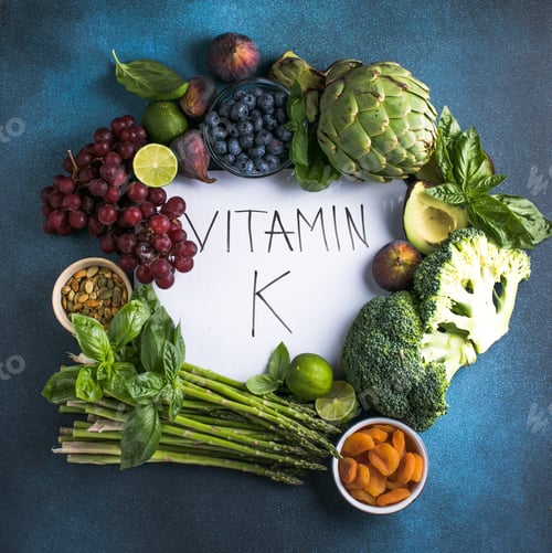 Preview: Vegetables, fruits and text Vitamin K on blue background. Top down view