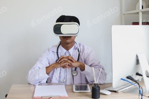 Preview: Young male doctor sitting while using virtual reality at the clinic