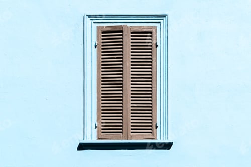 Preview: Gray shutters on the window against a blue colored wall. Old exterior in italian or greek village