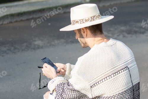 Preview: Model wears a white V-neck sweater, a pair of white jeans and a Panama hat