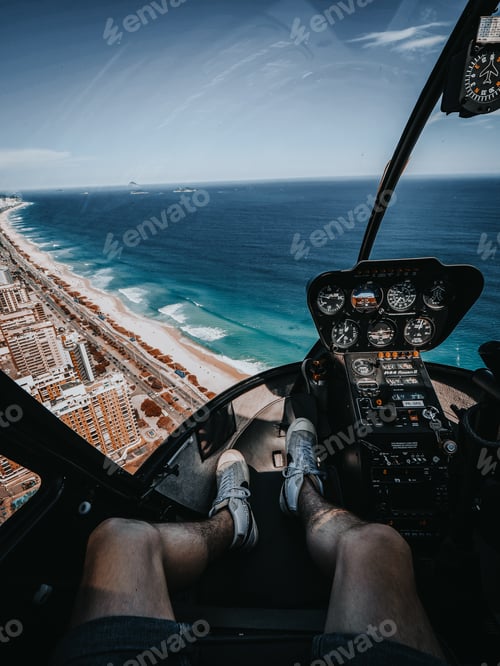 Preview: Vertical shot of a person sitting in a helicopter flying over the beach and ocean