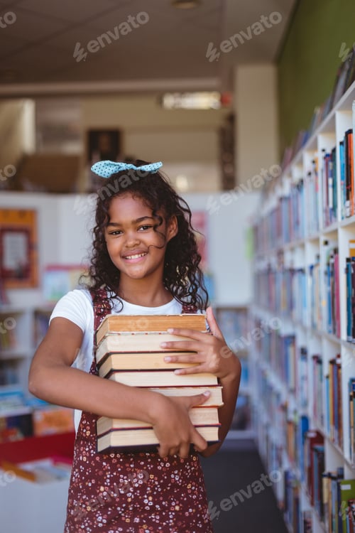 Preview: Portrait of smiling african american schoolgirl carrying stack of books in school library