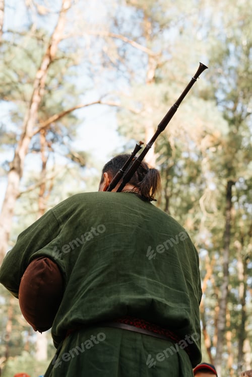 Preview: A musician playing the bagpipes at an outdoor music folk festival. Rear view, selective focus