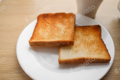 Preview: two pieces of toasted sliced bread on a white plate and coffee on wooden table, ready to do