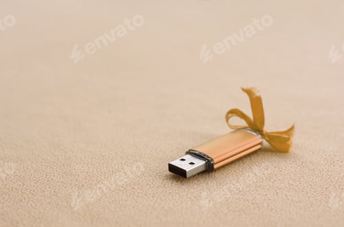 Preview: Orange usb flash memory card with a blue bow lies on a blanket of soft an