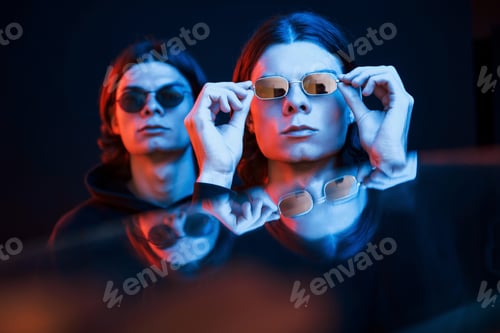 Preview: Artificial lighting. Portrait of twin brothers. Studio shot in dark studio with neon