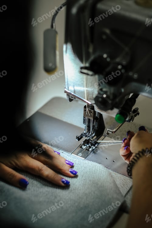 Preview: Vertical shot of female hands using a sewing machine