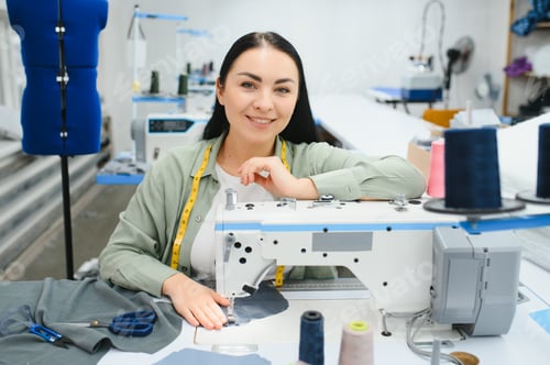 Preview: Young woman working as seamstress in clothing factory.