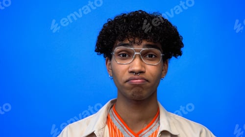 Preview: Displeased african american man in eyeglasses looking at camera isolated on blue