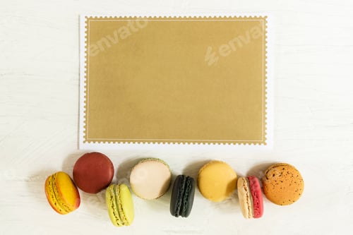 Preview: Food background, colorful french macaroons row on white background with empty brown paper for text.