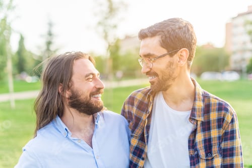 Preview: cheerful gay couple looking at each other in the park