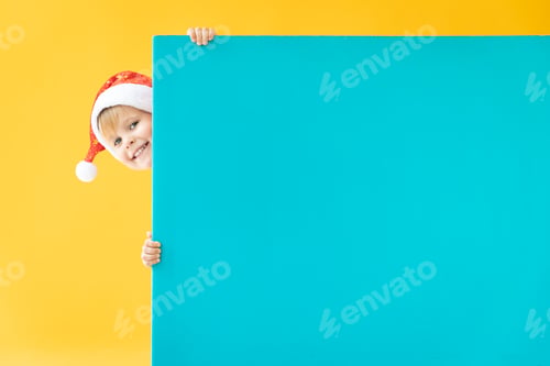 Preview: Smiling Child in Santa Hat Peeking Behind Sign
