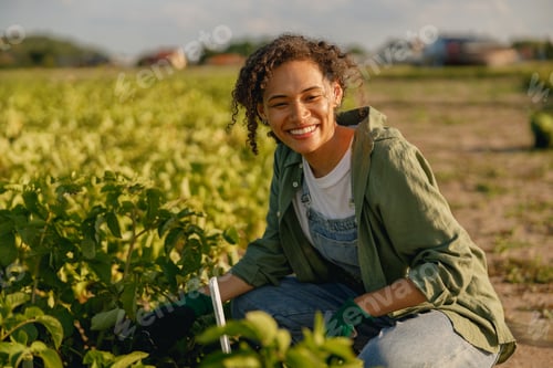Preview: Smiling woman farm worker working with the plants on field. Agriculture concept