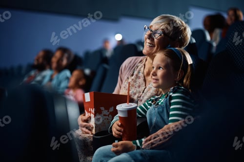 Preview: Happy little girl and her grandmother watching movie in cinema.