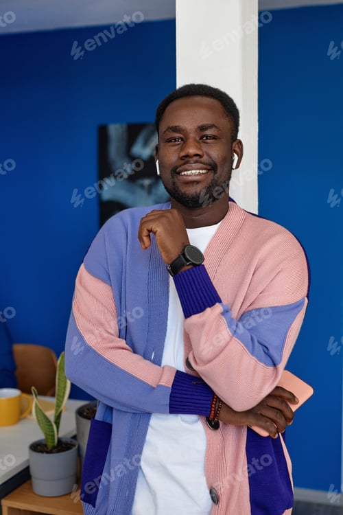 Preview: Black man wearing colorful clothes in office and smiling at camera