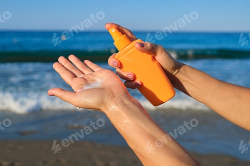 Preview: Close up of woman applying suntan lotion, sand beach blue sea background