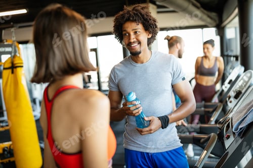 Preview: Happy friends enjoying break while chatting in the gym