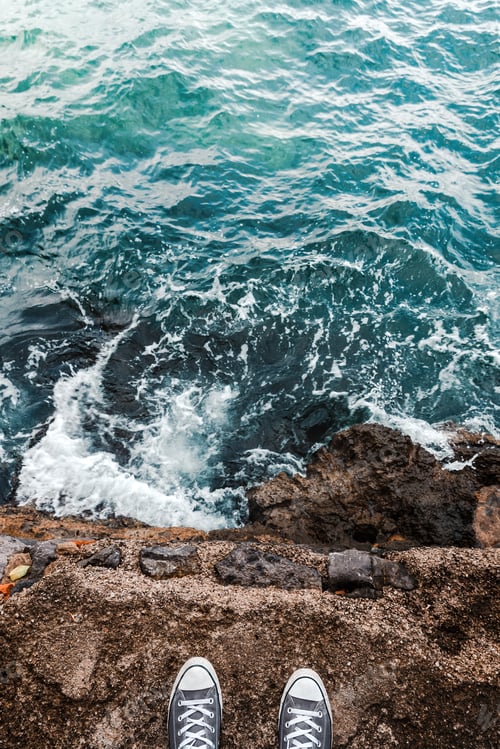 Preview: Suicidal ideation or thoughts, young person standing at the ocean cliff above the cold water