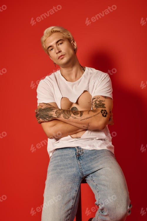 Preview: Stylish young man poses confidently against a vibrant red backdrop exuding youth culture