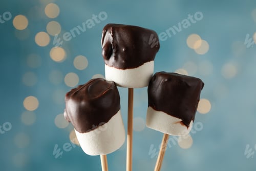Preview: Marshmallow in chocolate against blue background with blurred lights