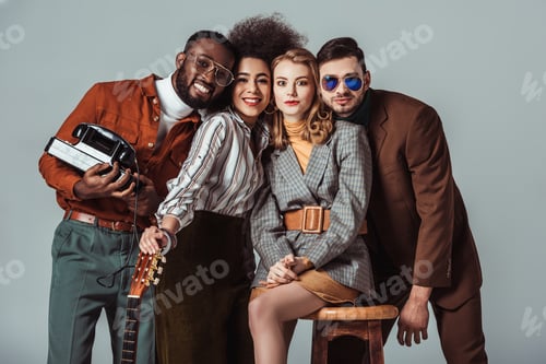 Preview: multicultural retro styled friends with guitar and telephone looking at camera isolated on grey