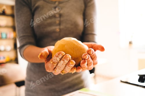 Preview: Woman holding dough with the ray of sun on her hands