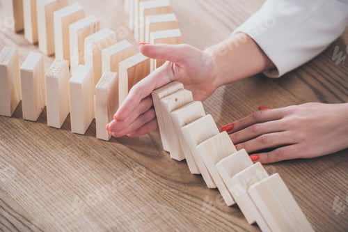 Preview: partial view of risk manager blocking domino effect of falling wooden blocks