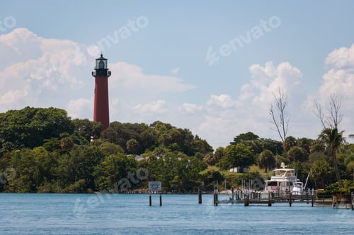 Preview: Lighthouse situated on a rocky coast surrounded by lush, green trees in Jupiter, Florida.