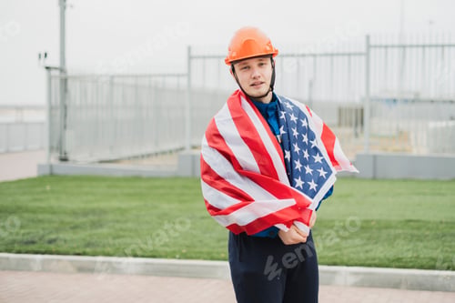 Preview: a patriontic american male worker holding usa national flag outdoors