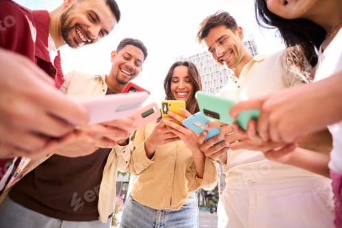 Preview: Group young people in circle using phones together outdoor. Cheerful friends meeting having fun.