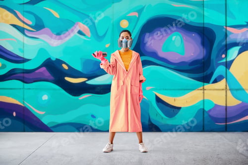 Preview: Graffiti woman painter in respirator mask standing near the wall with her paintings