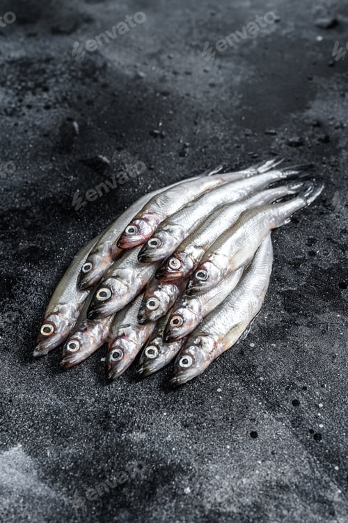 Preview: Fresh raw sea small fish smelt. Black background. Top view