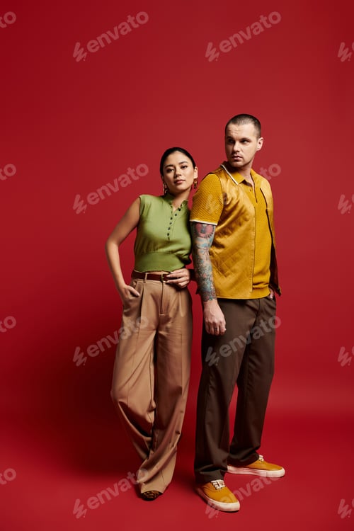 Preview: A beautiful young couple dressed in trendy outfits poses together in a bold studio backdrop.