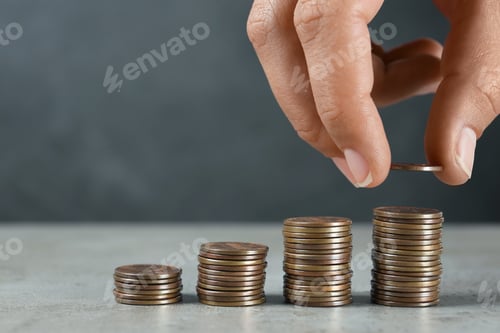 Preview: Young woman stacking coins on grey stone table, closeup view. Space for text