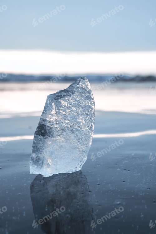Preview: A transparent icicle on the frozen surface of Lake Baikal in winter against the sky. Close-up.