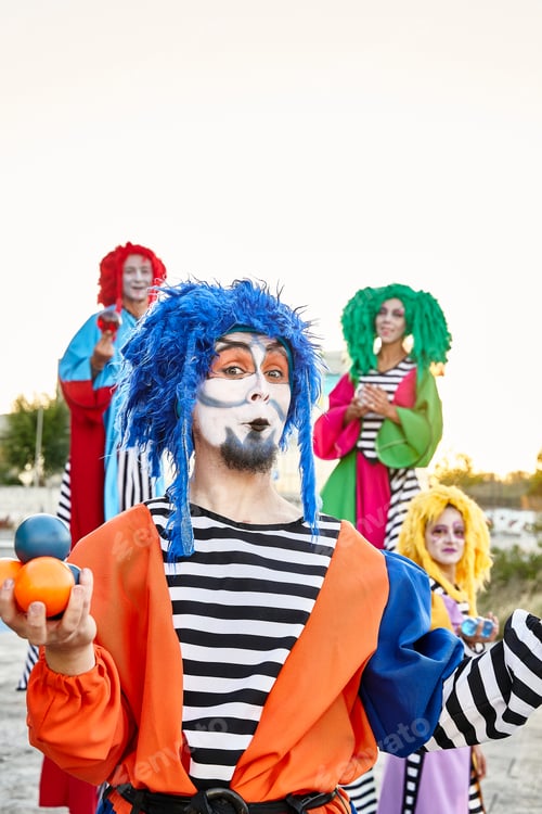 Preview: Group of harlequins in colorful costumes holding crystal balls.