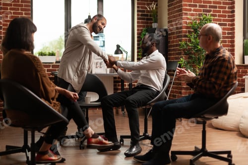 Vista previa: Personas multiétnicas dan un apretón de manos para celebrar el progreso en una terapia de grupo