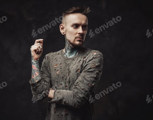 Preview: Pensive hipster poses in dark background in ragged shirt