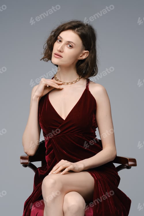 Preview: Young woman sits on tall chair in dress